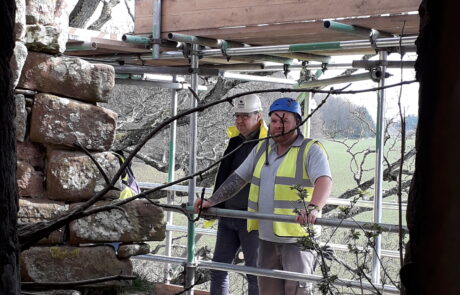 Image of two people standing on scaffolding looking at stonework