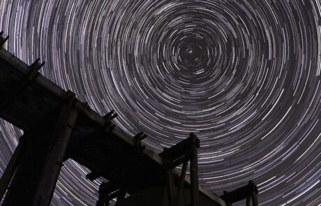 Stars above mine machinery Image of star trails against dark sky with silhouette of mine machinery