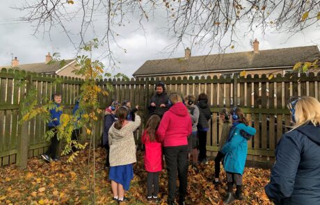 Image of group of children standing listening in the corner of a garden
