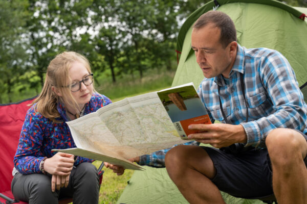 The image shows me and a colleague sitting outside looking at a map of the Fellfoot Forward scheme area. There are trees and a tent behind us. 