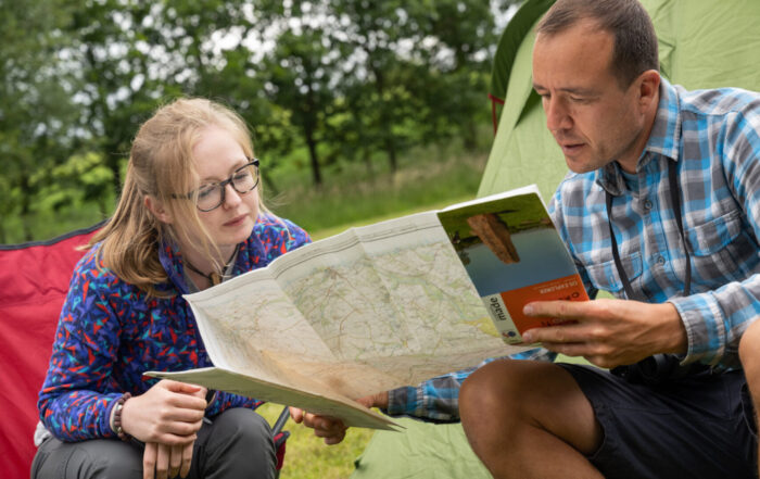 The image shows me and a colleague sitting outside looking at a map of the Fellfoot Forward scheme area. There are trees and a tent behind us.