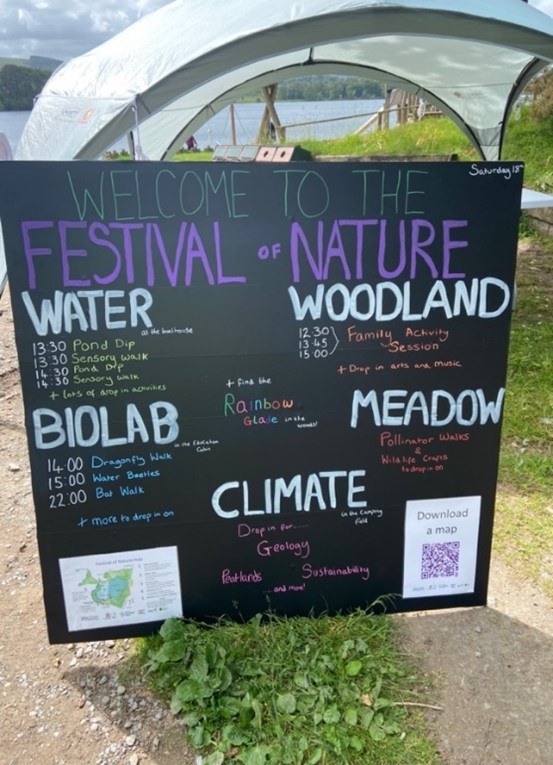 The image shows blackboard with colourful words stating 'Welcome to the Festival of Nature'. The blackboard shows various sessions taknig place under the headings 'Water', 'Woodland', 'Biolab', 'Meadow' and 'Climate. 