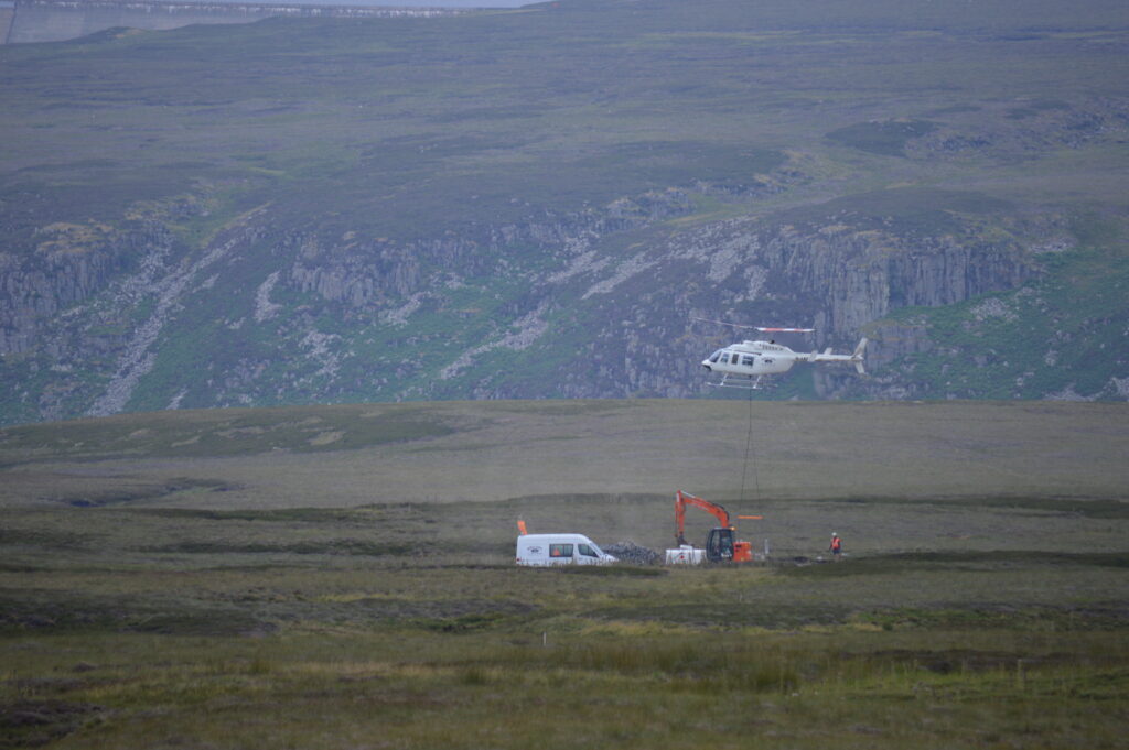 Helicopter airlifting a stone dam in the North Pennines National Landscape