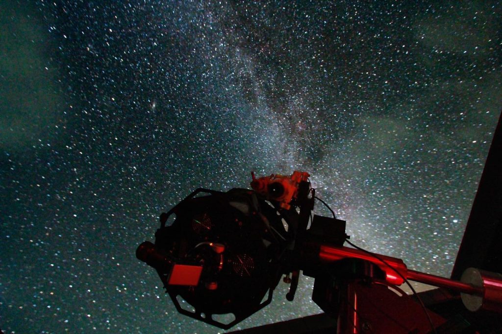 Large telescope at Grassholme Observatory in foreground. The telescope is facing up to a starry dark sky in the North Pennines.