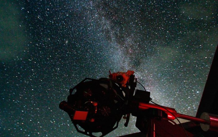 Large telescope at Grassholme Observatory in foreground. The telescope is facing up to a starry dark sky in the North Pennines.