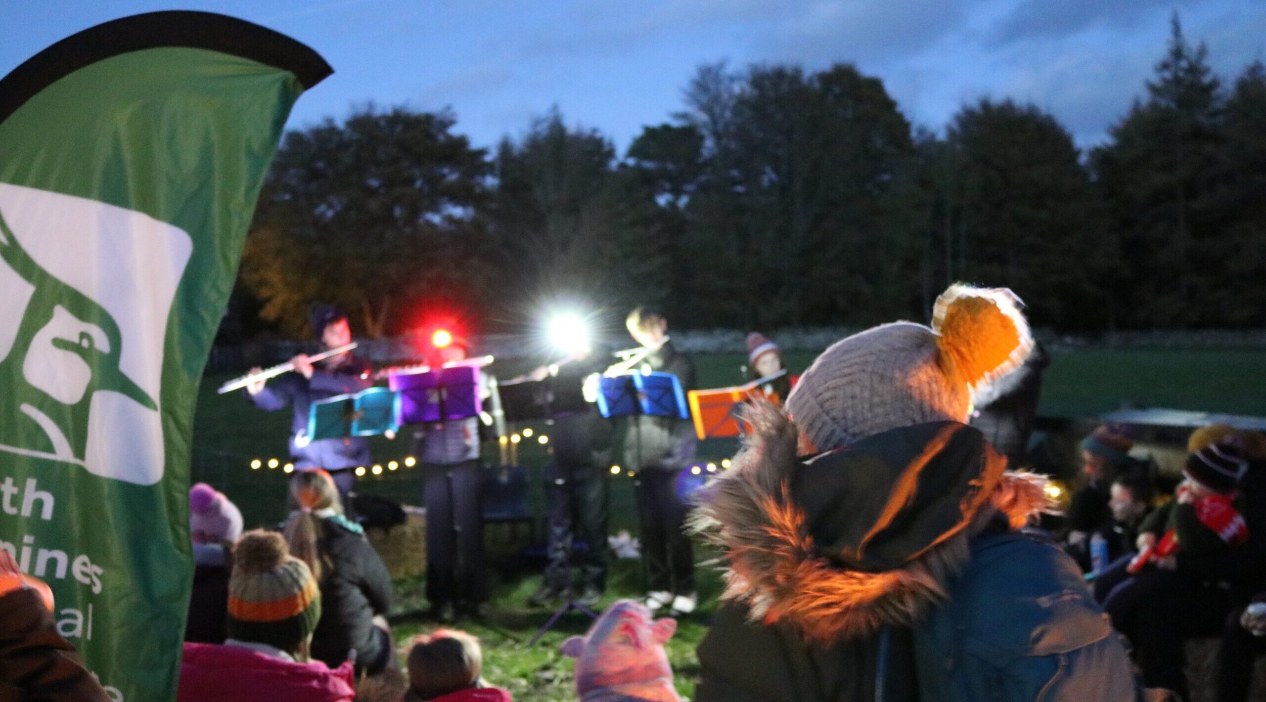 Stars and songs event at Bowlees Farm in Teesdale. Durham University flute choir perform outside in front of crowd dressed for winter.