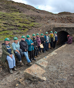 Photograph of group of women wearing hard hats at the entrance to a mine in the North Pennines