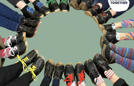 Clog workshops Photograph of a circle of feet wearing black leather clogs with different coloured laces