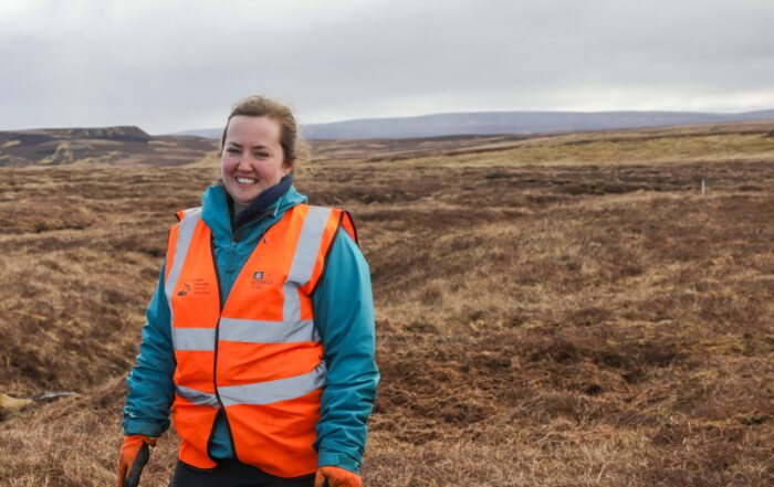 Senior peatland field officer in high-vis jacket smiling and standing on a North Pennines peatland.