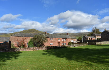 A line of red sandstone cottages with hills behind