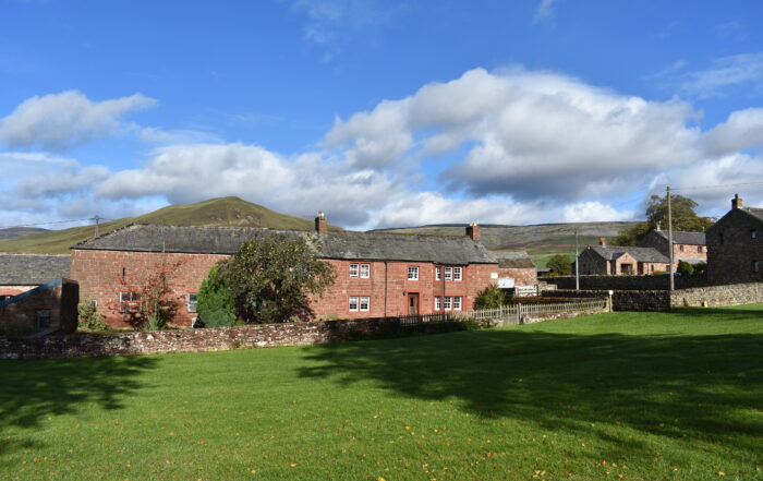 A line of red sandstone cottages with hills behind