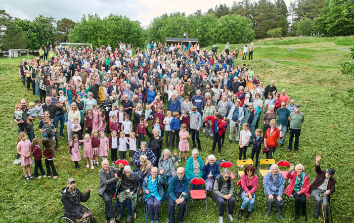 Group of people sitting and standing in a field for the Alston Moor community mass photo 2026